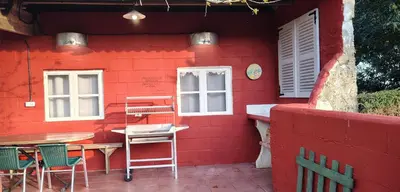 a red building with a table and chairs outside at Casa de Piñeiro y SPA Opcional con coste extra in Santiago de Compostela