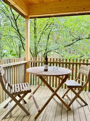 a picnic table and two chairs on a wooden deck at Cabañas Enoturismo María Manuela in Pousada