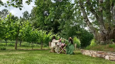 two women sitting at a table in the grass at Cabañas Enoturismo María Manuela in Pousada