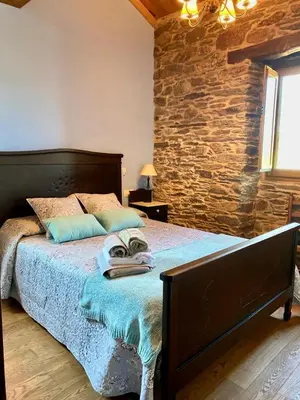 a bedroom with a bed with a stone wall at Casa Compostela in Bama