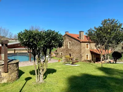 an old stone house with a tree in the yard at Casa Compostela in Bama