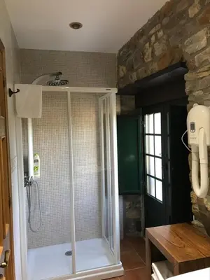 a bathroom with a shower with a glass door at Pensión Xacobe in Cabreiros