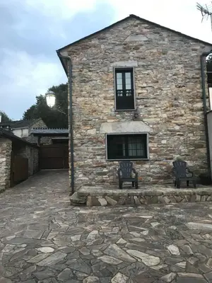 a stone building with two benches in front of it at Pensión Xacobe in Cabreiros
