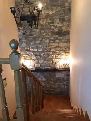 a staircase with a stone wall and a chandelier at Pensión Xacobe in Cabreiros