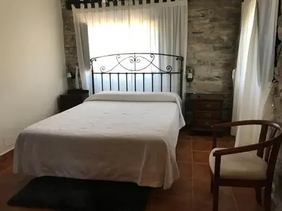 a bedroom with a bed and a chair and a window at Pensión Xacobe in Cabreiros