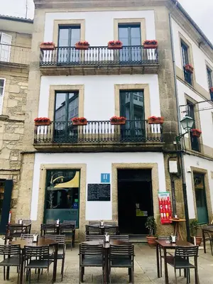 a building with tables and chairs in front of it at Hotel Arco de Mazarelos in Santiago de Compostela