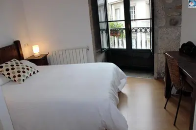 a bedroom with a bed and a desk and a window at Hotel Arco de Mazarelos in Santiago de Compostela