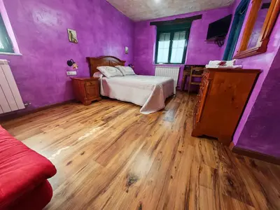 a purple room with a bed and a wooden floor at Hostería Casa Flor in Murias de Rechivaldo