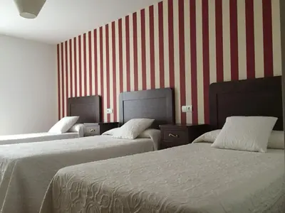 two beds in a room with red and white stripes at Hotel Rural Nova Ruta in Trabadelo
