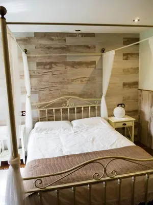 a bedroom with a bed with a wooden wall at Casas Rurales TAReira en Taramundi in Taramundi