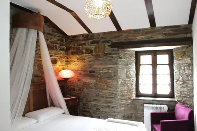 a bedroom with a bed and a window and a chandelier at Casas Rurales TAReira en Taramundi in Taramundi
