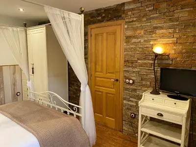 a bedroom with a bed and a tv and a brick wall at Casas Rurales TAReira en Taramundi in Taramundi