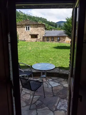 a patio with a table and chairs and a field at Casas Rurales TAReira en Taramundi in Taramundi