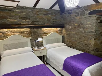 two beds in a room with a stone wall at Casas Rurales TAReira en Taramundi in Taramundi