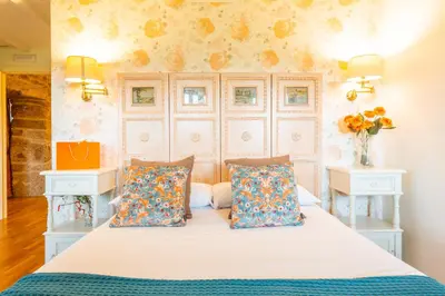 a bedroom with a bed with two night stands and two tables at Eira Grande Galicia Villas in Pedre
