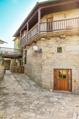 a stone building with a wooden door and a balcony at Eira Grande Galicia Villas in Pedre