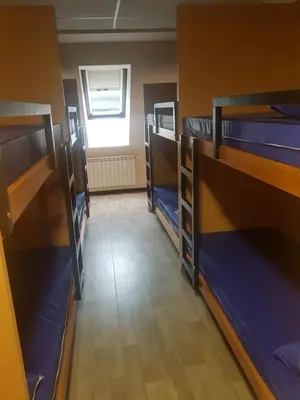 a room with several bunk beds and a window at Albergue Piñeiral Fonsagrada in Fonsagrada