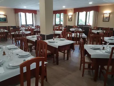 a dining room with tables and chairs and windows at Albergue Piñeiral Fonsagrada in Fonsagrada