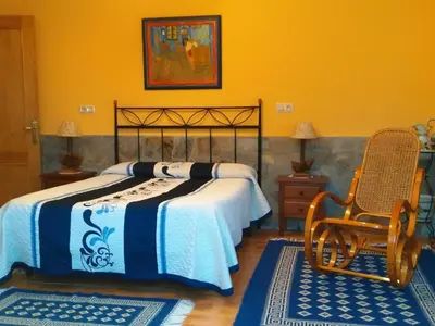 a bedroom with a bed and a chair and two rugs at Apartamentos Rurales Casa El Caminero in Merás