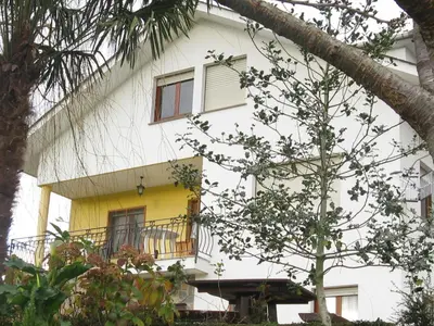 a white building with a balcony and a tree at Apartamentos Rurales Casa El Caminero in Merás
