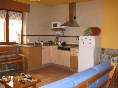 a kitchen with a white refrigerator and a table at Apartamentos Rurales Casa El Caminero in Merás