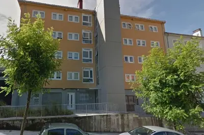 an apartment building with two cars parked in front of it at Alojamiento ideal en Santiago in Santiago de Compostela