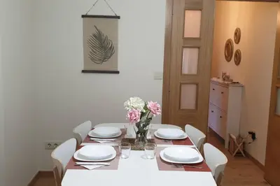 a dining room table with white plates and flowers on it at Alojamiento ideal en Santiago in Santiago de Compostela