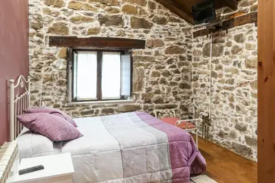a bedroom with a bed in a stone wall at Spacious House with Jacuzzi, Mountain View near Tineo in Tineo