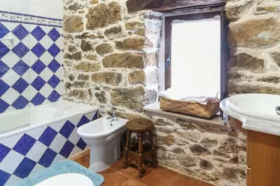 a bathroom with a stone wall and a sink and a toilet at Spacious House with Jacuzzi, Mountain View near Tineo in Tineo