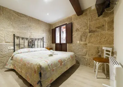a bedroom with a bed in a stone wall at Gran Casa Rural A Touza in Ourense