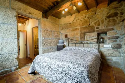 a bedroom with a bed in a stone wall at Gran Casa Rural A Touza in Ourense