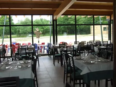 a dining room with tables and chairs and windows at Camping Vila de Sarria in Sarria