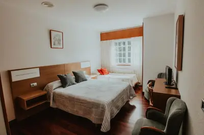 a hotel room with two beds and a television at Hotel A Veiga in Samos