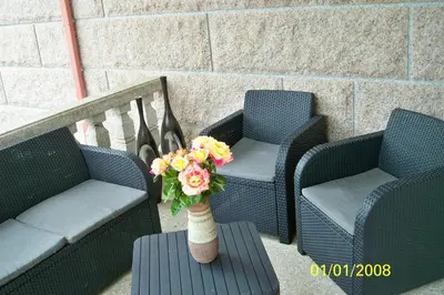 two chairs and a vase with flowers on a patio at POSTA Do SOL in Baralla