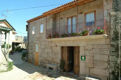a stone building with a balcony with flowers on it at Casa Rural Vilaboa in Allariz