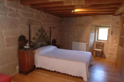 a bedroom with a bed in a stone wall at Casa Rural Vilaboa in Allariz