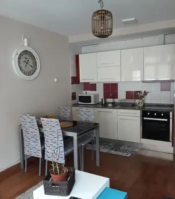 a kitchen with a table and a clock on the wall at Apartamento Cine Colón 2 in Ribadeo