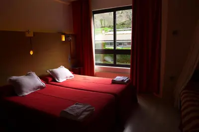 a hotel room with two beds and a window at Hotel Castillo del Alba in Pola de Somiedo
