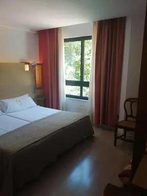 a hotel room with a bed and a window at Hotel Castillo del Alba in Pola de Somiedo