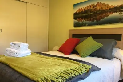 a bed with colorful pillows and a painting on the wall at PISO A 400 METROS DE LA CATEDRAL in Santiago de Compostela