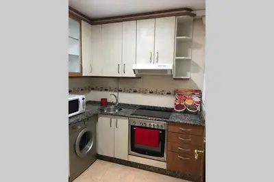 a kitchen with white cabinets and a washer and dryer at PISO A 400 METROS DE LA CATEDRAL in Santiago de Compostela