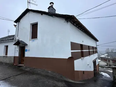 a white building with a cross on the side of it at La Casa del Maestro in Rabanal