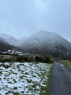 a snow covered road with mountains in the background at La Casa del Maestro in Rabanal