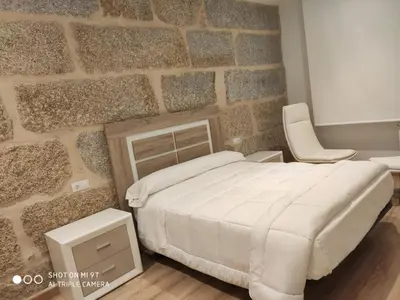 a bedroom with a bed and a stone wall at Villa Trabazos Abellas in Ourense