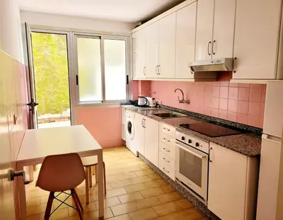 a kitchen with white cabinets and a table and a sink at Amplio piso con terraza en el Camino y Catedral in Santiago de Compostela