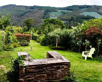 a stone bench and a chair in a field of grass at Casa Nastasia in A Pontenova