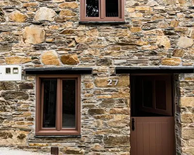 a stone building with two windows and a door at Casa Nastasia in A Pontenova
