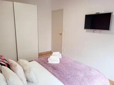a bedroom with a bed with a tv on a wall at AMPLIO PISO LUMINOSO CERCA DEL CAMINO Y CATEDRAL C3 in Santiago de Compostela