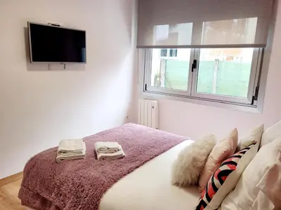 a bedroom with a bed with a pink blanket and a tv at AMPLIO PISO LUMINOSO CERCA DEL CAMINO Y CATEDRAL C3 in Santiago de Compostela