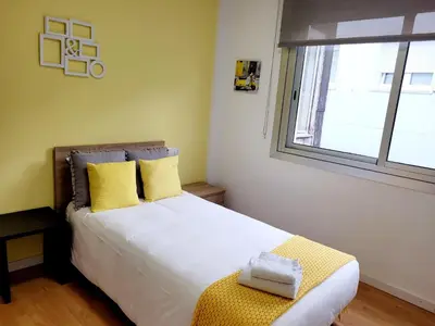a bedroom with a bed with yellow pillows and a window at Amplio piso con vistas en la entrada del camino C4 in Santiago de Compostela